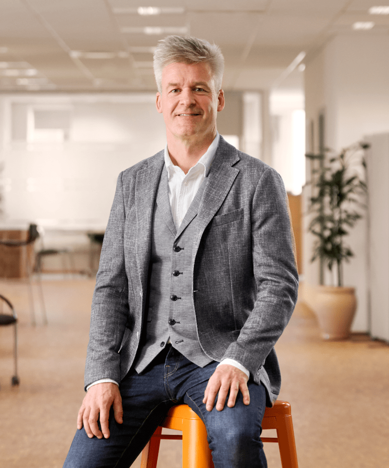 Mand i gråt jakkesæt sidder på orange skammel